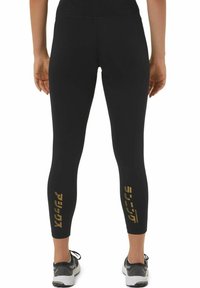 Black athletic leggings with a smooth texture, featuring gold printed accents on the lower legs and a fitted design.