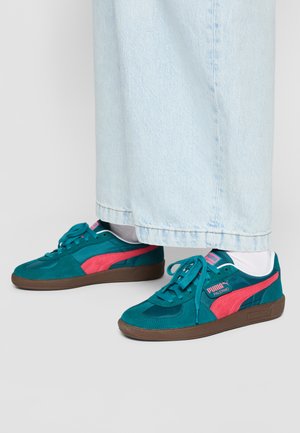 Baskets en daim bleu-vert avec des accents roses, bout rond et lacets. Présentant une semelle extérieure marron et une étiquette de marque sur le côté.