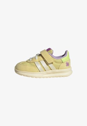 Sneaker giallo in suede con tre strisce bianche, cinturino in velcro e accenti viola chiaro. Suola leggera e colletto imbottito per il massimo comfort.