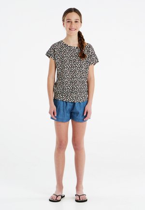 T-shirt nera a fiori con maniche corte, abbinata a pantaloni shorts in denim blu. L'outfit presenta una vestibilità comoda e uno stile informale.