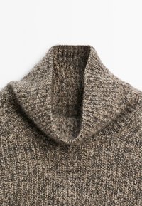 Maglione a collo alto a coste marrone e beige, con il collare piegato su uno sfondo bianco uniforme.