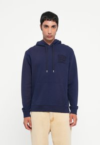 Navy blue hoodie made of soft fabric, featuring a front pocket, adjustable drawstrings, and embossed logo on the left chest.