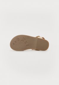 Bruine rubberen zool met een vlinderpatroon, met een gladde textuur en een plat ontwerp. De randen zijn licht afgerond met een matte afwerking.