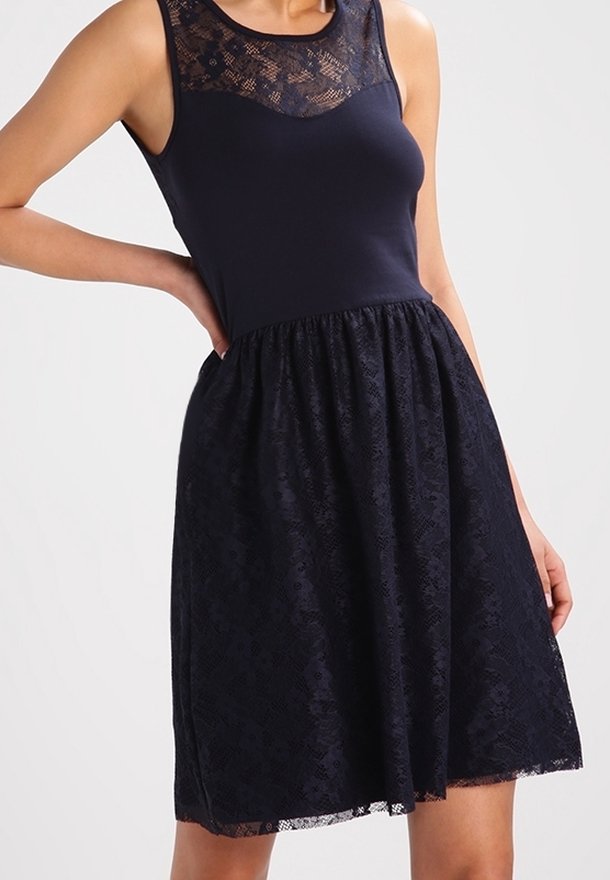 Marindräkt med en åtsittande bodice och spetsöverdrag. Ärmlös design med en strukturerad spetsskjorta som har blommönster och en utsvängd form.