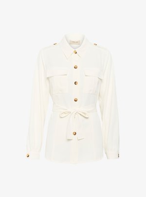 Camicia bianca con maniche lunghe, chiusura a bottoni, due tasche sul petto e una cintura annodata in vita. Presenta bottoni con finitura dorata e una consistenza morbida.