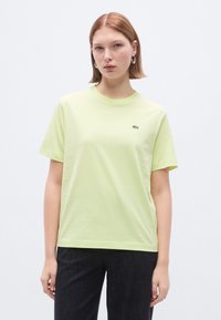 Λαχανί βαμβακερό μπλουζάκι με στρογγυλή λαιμόκοψη και κοντά μανίκια. Διαθέτει μικρό πράσινο λογότυπο Lacoste στο αριστερό στήθος.