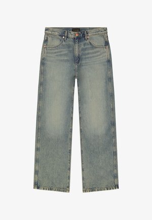 Meeste Wrangler sirge säärega sinised teksad tuhmunud detailide, vasksete naelte ja viiepokilisel stiilil, valgel taustal.