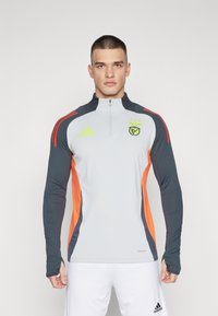 Light gray athletic long-sleeve top with dark blue and orange accents, half-zip collar, embroidered logo, and ribbed sleeve cuffs.