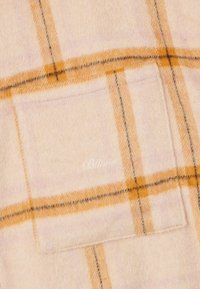 Jasnoróżowa flanelowa tkanina w pomarańczowo-czarny wzór w kratę, z małą kieszonką na piersi i białym haftowanym logo.