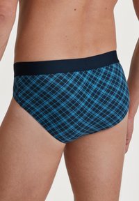 Männer Slip aus weichem Stoff mit einem blau-schwarzen Karomuster. Elastischer Bund, figurbetonte Passform und glatte Textur.