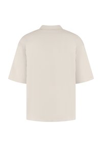 Lichtbeige polo-shirt met korte mouwen, kenmerken van een klassieke kraag, zachte textuur en een relaxte pasvorm. Geen zichtbare logo's of patronen.