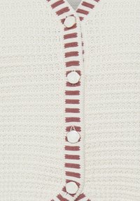 Kreemikas kootud kampsun lähedalt, millel on valgete nuppude vertikaalne rida ja roosade triipudega ääris nööpide joone ääres.