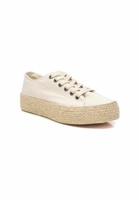 Zapatillas de lona en beige con punta redonda, cierre de cordones en la parte delantera y suela de plataforma de yute texturizada. Incluye ojales de metal negro y detalles de costura.