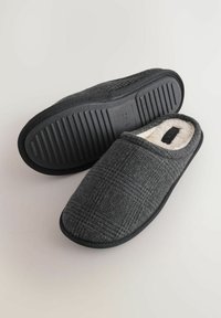 Zapatillas de tela gris con un patrón de cuadros texturizado, que cuentan con un suave forro blanco y una suela de goma con diseño estriado para mejor agarre.
