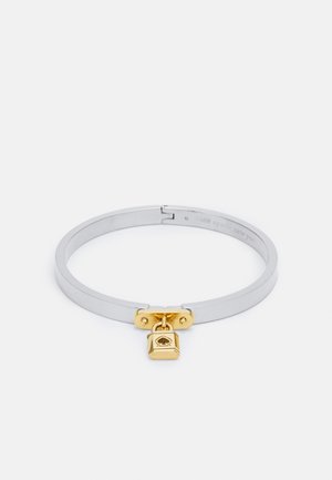 Silbernes Metallarmband mit einem goldenen Vorhängeschlossverschluss, das ein Herzsymbol zeigt. Glatte Textur, elegantes Design und eine minimalistische Form.