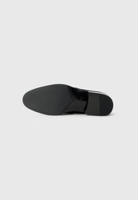 Chaussures noires avec une tige en cuir lisse et un bout arrondi. La semelle est plate et en caoutchouc avec un motif pour une meilleure adhérence.