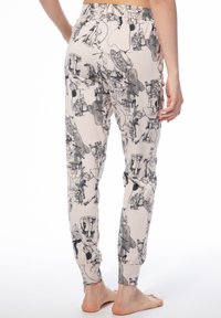 Baumwoll-Jogginghosen mit einem hellbeigen Hintergrund, versehen mit schwarzen Skizzen verschiedener Charaktere, elastischem Bund und elastischen Säumen.