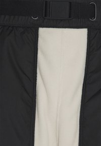 Svarta isolerade byxor med en krämfärgad fleecefoder. Har en siddragkedja och ett svart justerbart bälte med en logobältesspänne.