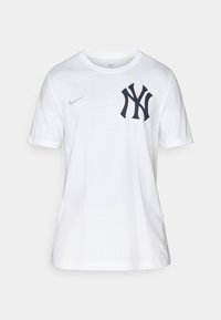 White cotton t-shirt featuring a navy blue New York Yankees logo on the left chest and a small gray Nike swoosh on the right sleeve.