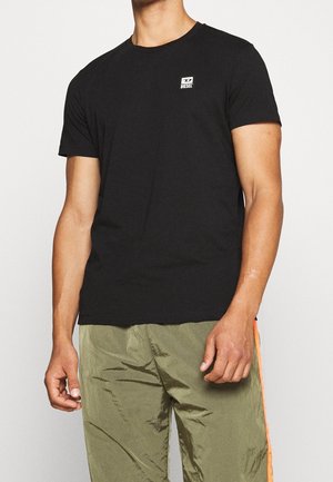 T-shirt en coton noir avec un col rond, des manches courtes et un petit logo Diesel blanc sur la poitrine. Assorti à un pantalon vert olive.