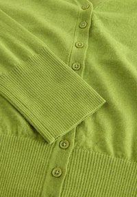 Cardigan vert en maille avec poignets et ourlet côtelés, doté d'une rangée de boutons verts sur le devant.