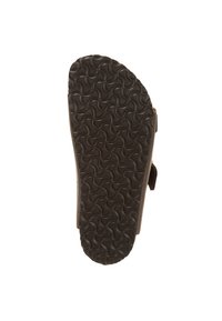 Brun sandal med en strukturerad svart gummisula med ett vågigt mönster, designad för komfort och stabilitet. Justerbar rem synlig.