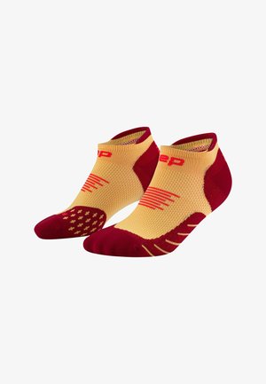 Rote und gelbe Sportsocken mit einem niedrigen Schnitt. Hergestellt aus strukturierter Stoff, der Rutschmuster an der Sohle und diagonale Streifen aufweist.