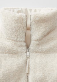 Leren fleece jack met ritssluiting in crème, met een hoge kraag, een gestructureerde buitenkant en een contrasterende zilveren rits met een stoffen trekhaak.
