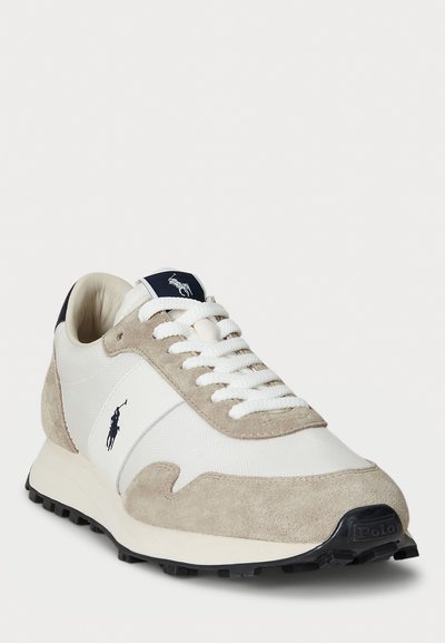 Baltas un bēšs ādas sneakers ar baltiem šņorēm, melns Polo logos sānos un melna zole ar teksturētu protektoru.