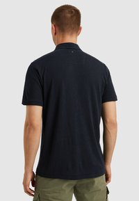 Navy modrá polo triko vyrobené z měkké bavlny, s klasickým límečkem, krátkými rukávy a malým logem na zádech.