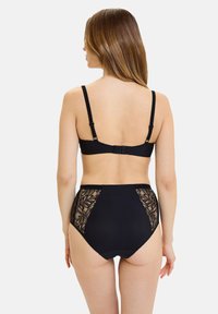 Sujetador inalámbrico negro y bragas de talle alto con paneles laterales de encaje. Tejido liso con detalles de encaje texturizado, tirantes ajustables.