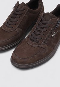 Baskets en daim marron avec accents en cuir, dotées d'un design à lacets et d'une fermeture éclair latérale, dessus texturé et semelle en caoutchouc.