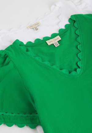 Grønne og hvide toppe med bølgede V-udskæringer og pufærmer, stablet med synlige størrelsesmærker "Love & Roses".