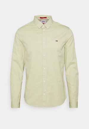 Camicia a maniche lunghe color giallo chiaro in cotone, con colletto alla camicia e una piccola patch del logo sul lato sinistro del petto.