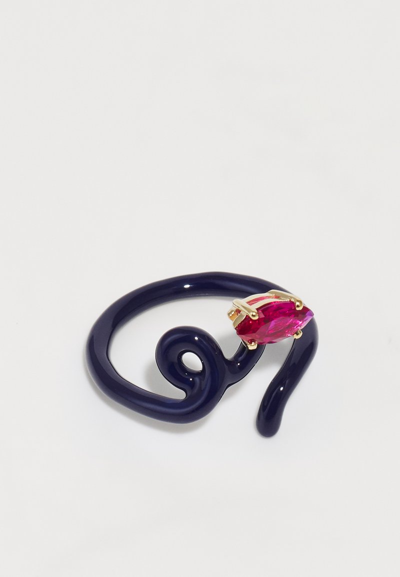 Tume lilla, paindlik rõngas keerukate mustritega, mille keskmes on silmapaistev roosa kivi kullatud metallist. Üksluiselt sile tekstuur ja modernne kuju.