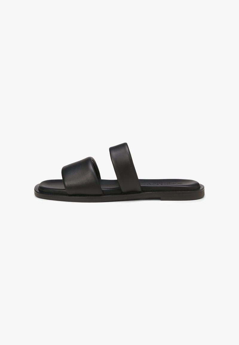 Mule plate noire avec deux larges brides en cuir et une semelle rembourrée, vue de profil sur un fond blanc.