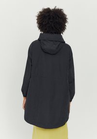Czarna kurtka z kapturem o luźnym kroju i długich rękawach, z lekko zaokrąglonym dołem i gładką fakturą. Widok od tyłu, bez widocznych detali.