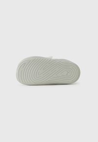 Semelle en caoutchouc de basket légère verte avec un motif de bande de roulement ondulé. La base présente des rainures texturées pour une meilleure adhérence et durabilité.