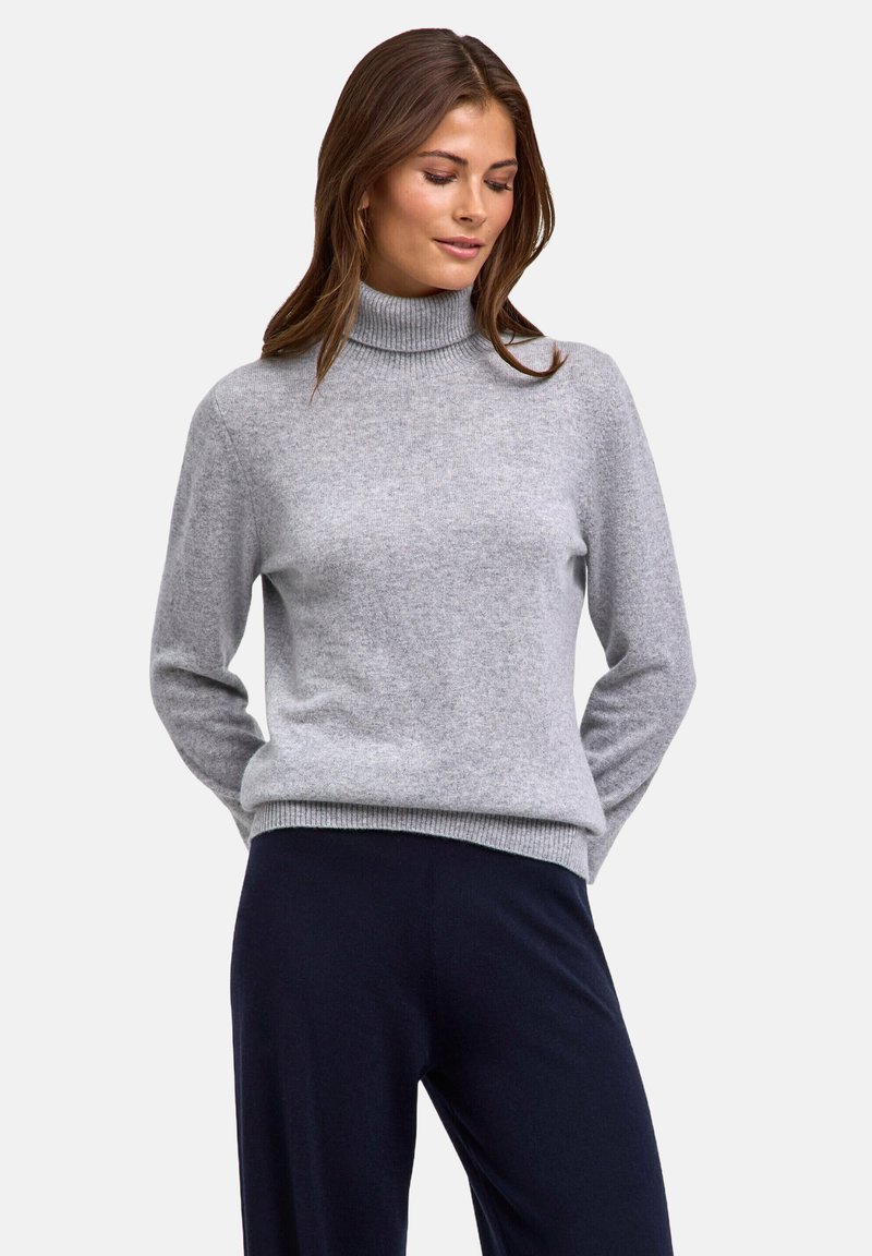Maglione a collo alto di colore grigio chiaro realizzato in tessuto morbido. Presenta maniche lunghe e orlo a coste. Abbinato a pantaloni di colore scuro.