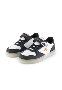 Baskets blanches et noires avec une finition en cuir lisse, conçues avec un devant à lacets, une sangle Velcro, une semelle transparente et un accent logo.