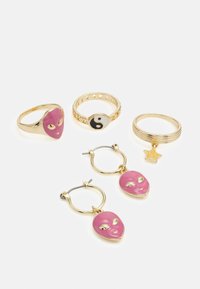 Quatro anéis e um par de brincos apresentam metal em tom dourado. Três anéis têm designs de alienígenas cor-de-rosa e yin-yang; os brincos exibem encantos de alienígena correspondentes.