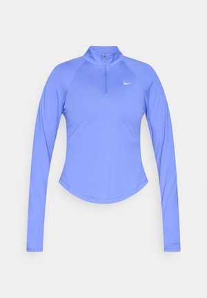 Hellblaues Sportoberteil mit langen Ärmeln und Halb-Reißverschluss am Kragen, mit einer geschwungenen Saumlinie und einem kleinen weißen Logo auf der linken Brustseite.