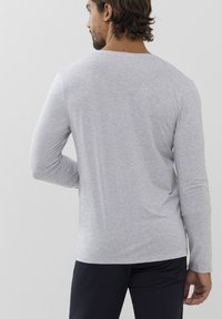 Maglietta a maniche lunghe grigia realizzata in morbido cotone misto. Presenta un colletto a girocollo, una vestibilità aderente e un tessuto liscio con una leggera trama.