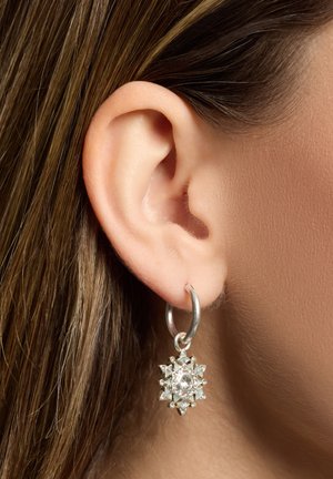 Silberner Creolenohrring mit einem sternförmigen Anhänger, verziert mit einem zentralen klaren Edelstein und kleineren dreieckigen Akzenten, ausgestattet mit einer strukturierten Oberfläche.