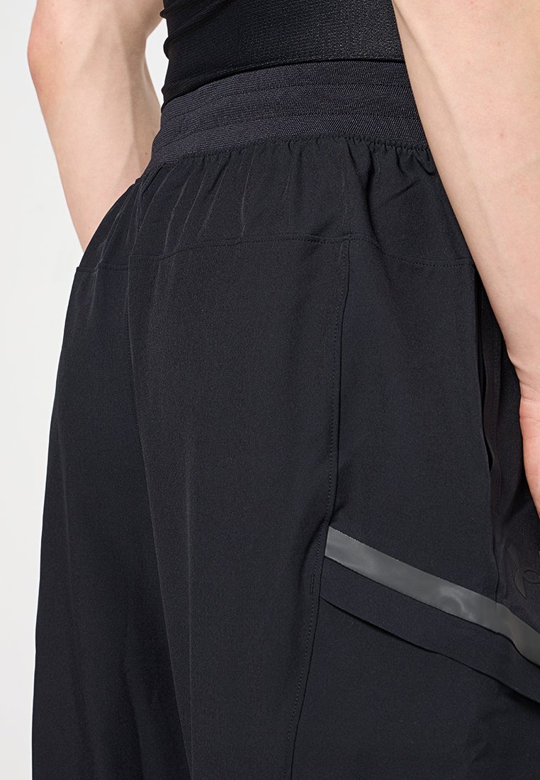 Pantalones cortos deportivos negros con una cinturilla elástica, que cuentan con una franja reflectante en el costado y una textura de tela suave y ligera.