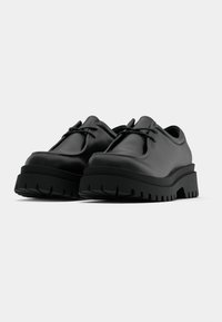 Schwarze Lederschuhe mit abgerundeter Spitze, detaillierten Schnürsenkeln und dicken, strukturierten Gummisohlen. Verfügen über eine breite Plattform für Stabilität.