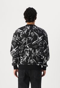 Black sweatshirt with white abstract patterns, long sleeves, ribbed cuffs and hem, featuring a logo tag at the lower side.
