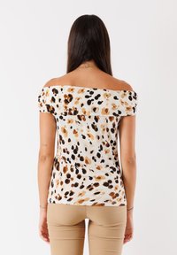 Top a spalle scoperte e maniche corte in tessuto leggero, caratterizzato da un mix di fantasie leopardate nei colori nero, marrone e crema.