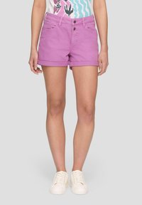 Shorts en denim violet avec un ourlet replié, style cinq poches et fermeture à deux boutons. Associés à des baskets blanches à lacets.
