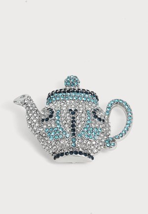 Broche en forme de théière décorée de petits strass bleus, noirs et transparents sur une base en métal argenté.